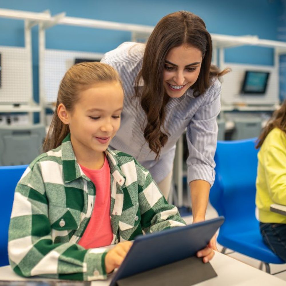 Woman looking into tablet of happy girl